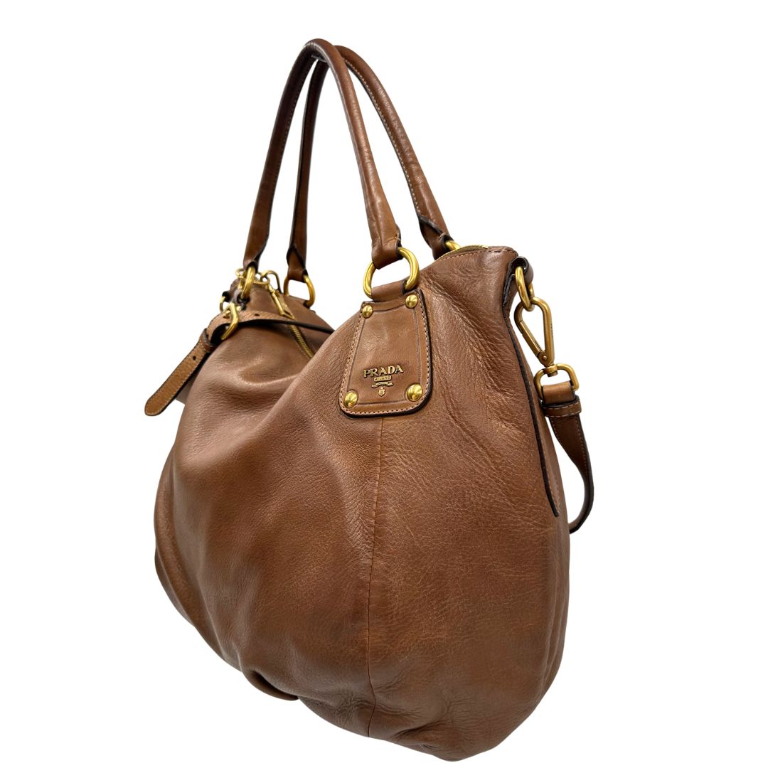 Laterale, Capiente borsa Prada in pelle marrone con hardware dorato, munita di doppi manici stondati e una tracolla regolabile ed amovibile. Originale, usata, di lusso, in ottime condizioni.