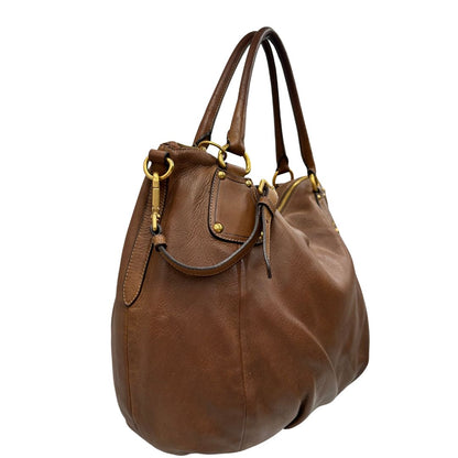 Laterale, Capiente borsa Prada in pelle marrone con hardware dorato, munita di doppi manici stondati e una tracolla regolabile ed amovibile. Originale, usata, di lusso, in ottime condizioni.