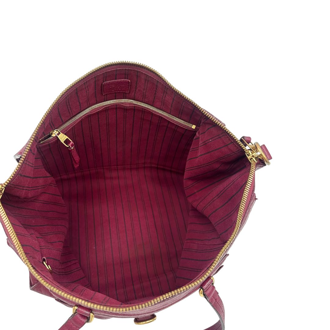 Interno, Louis Vuitton in pelle monogram empreinte color magenta con hardware dorato , munita di doppi manici. Indossabile a spalla. Originale, usata, di lusso, in ottime condizioni.