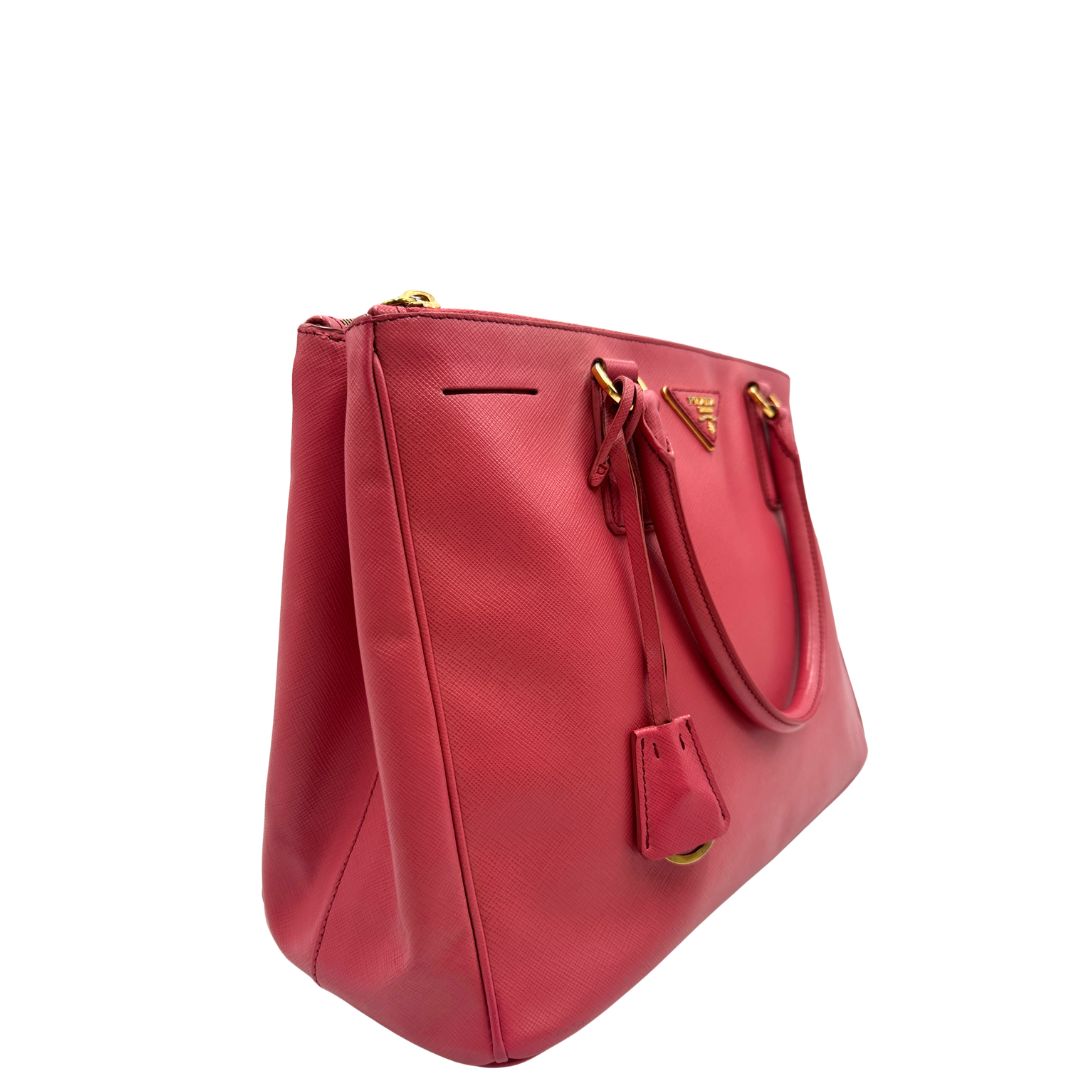 lato  Borsa Prada in pelle saffiano color rosa fragola con hardware dorato, di lusso, originale, ottime condizioni, usata 