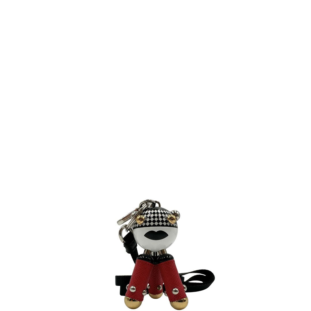 Charm Prada presenta una testa a sfera con un motivo a scacchi bianchi e neri e dettagli metallici color oro, le gambe sono realizzate in pelle saffiano rossa. Originale, usato, di lusso, in condizioni eccellenti.