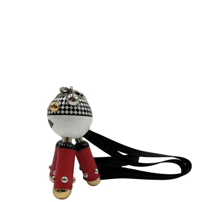 Charm Prada presenta una testa a sfera con un motivo a scacchi bianchi e neri e dettagli metallici color oro, le gambe sono realizzate in pelle saffiano rossa. Originale, usato, di lusso, in condizioni eccellenti.