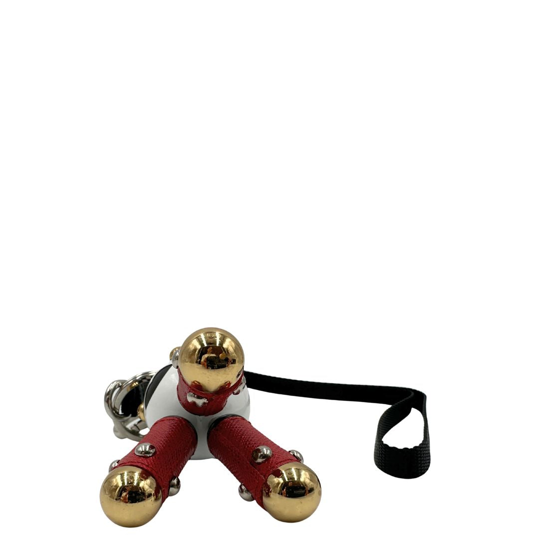 Charm Prada presenta una testa a sfera con un motivo a scacchi bianchi e neri e dettagli metallici color oro, le gambe sono realizzate in pelle saffiano rossa. Originale, usato, di lusso, in condizioni eccellenti.
