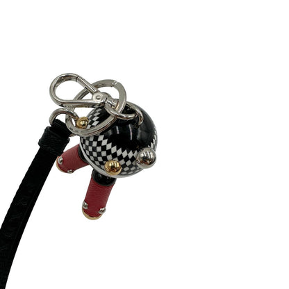 Charm Prada presenta una testa a sfera con un motivo a scacchi bianchi e neri e dettagli metallici color oro, le gambe sono realizzate in pelle saffiano rossa. Originale, usato, di lusso, in condizioni eccellenti.