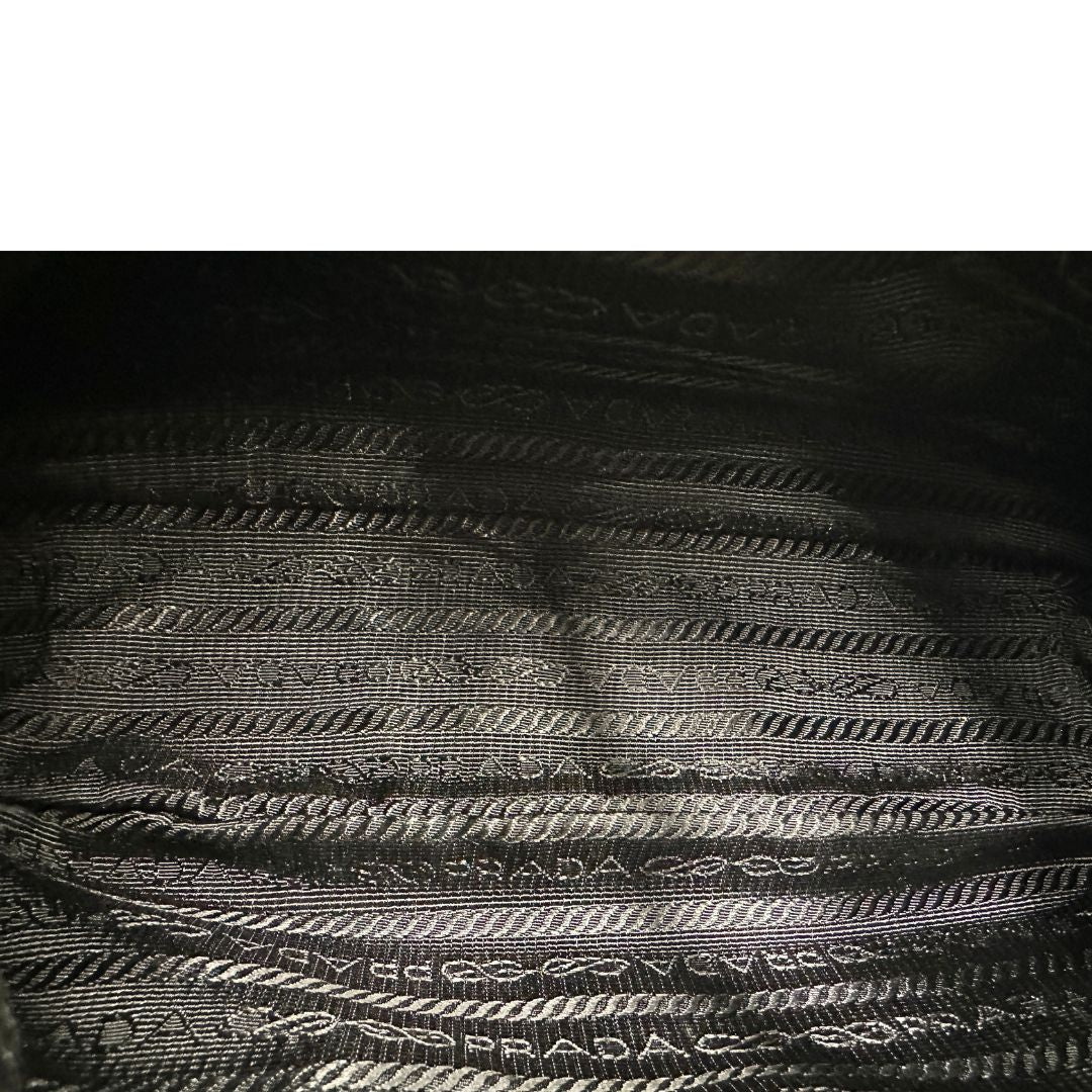 Interno, Borsa Prada in re-nylon nero con finiture in pelle saffiano tono su tono; indossabile a spalla. Originale, usata, di lusso, in ottime condizioni.