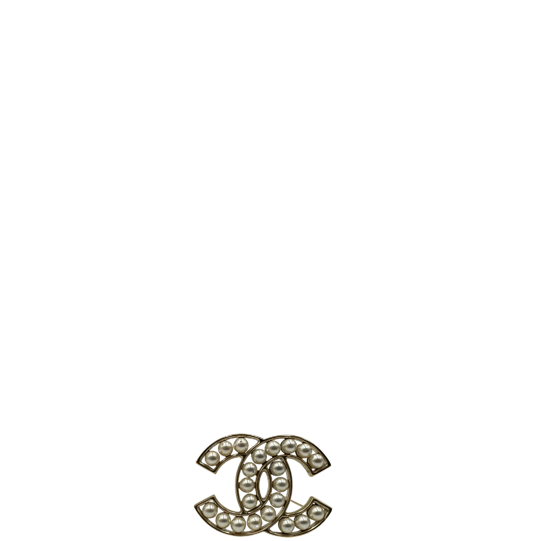 Elegante Spilla Chanel con iconico logo CC intrecciato in metallo dorato, impreziosito di perle decorative. Originale, usata, di lusso, in ottime condizioni.