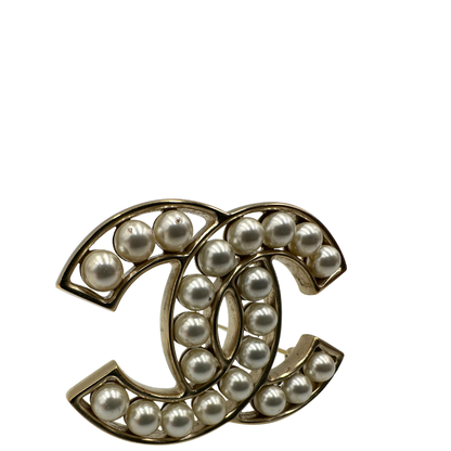 Elegante Spilla Chanel con iconico logo CC intrecciato in metallo dorato, impreziosito di perle decorative. Originale, usata, di lusso, in ottime condizioni.