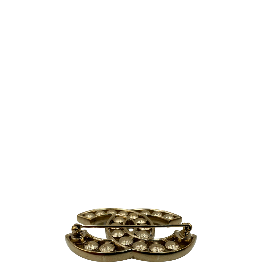 Elegante Spilla Chanel con iconico logo CC intrecciato in metallo dorato, impreziosito di perle decorative. Originale, usata, di lusso, in ottime condizioni.