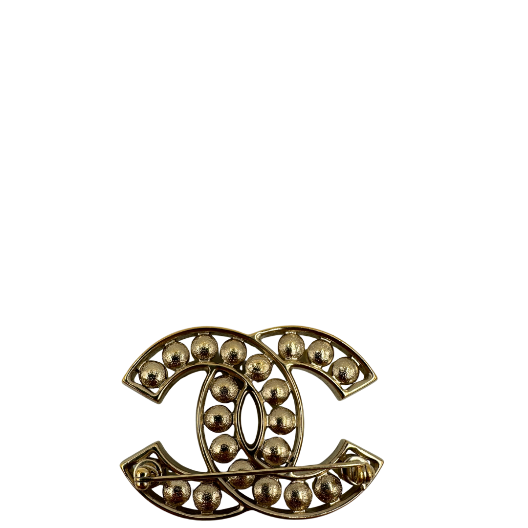 Retro, Elegante Spilla Chanel con iconico logo CC intrecciato in metallo dorato, impreziosito di perle decorative. Originale, usata, di lusso, in ottime condizioni.