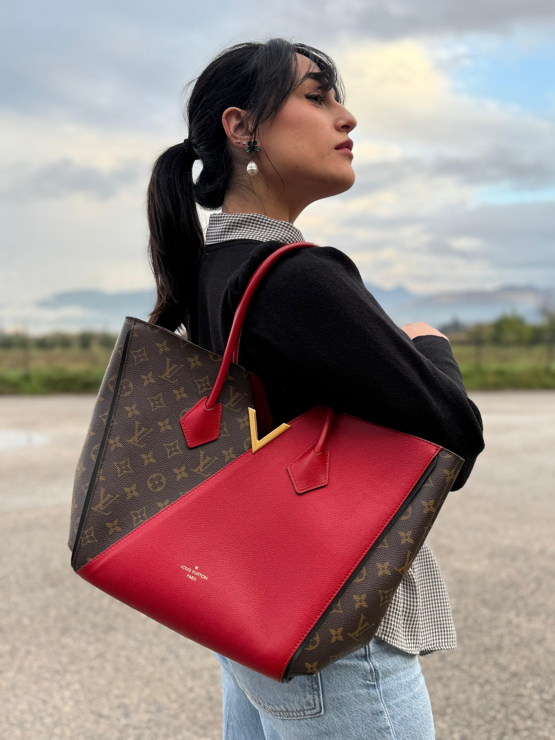Ragazza che indossa una borsa Louis Vuitton modello Kimono Tote, in canvas monogram e pelle rossa.
Struttura con pannelli incrociati e inserto frontale con elemento metallico a forma di V in finitura dorata. Manici superiori in pelle. Dotata di dustbag. Indossabile a spalla.