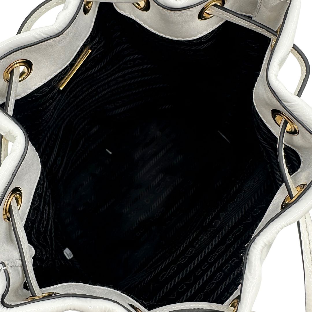 interno Secchiello Prada in pelle verniciata bianca con parti metalliche dorate; munito di un manico singolo e una tracolla amovibile e regolabile, di lusso, originale, ottime condizioni, usato. 