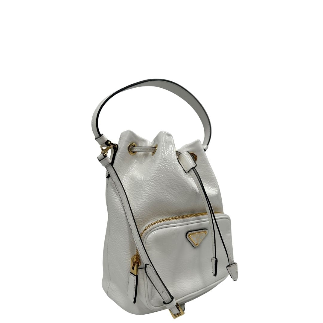 lato Secchiello Prada in pelle verniciata bianca con parti metalliche dorate; munito di un manico singolo e una tracolla amovibile e regolabile, di lusso, originale, ottime condizioni, usato. 